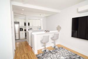 a white kitchen with a bar and two chairs at The Gray Loft Escape NYC Edition. in New York +38 photos