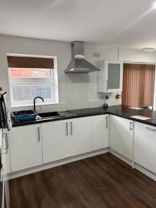 een keuken met witte kasten en zwarte aanrechtbladen bij EM HOME - Room 4 in Nottingham