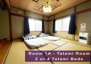 due letti in una stanza con due finestre di Furano House, 1F Apartment, 2 Bedrooms, Max 8PP - 6 Adults 2 Kid, Near JR, Group Travel, Onsite Parking a Furano Altre 8 foto