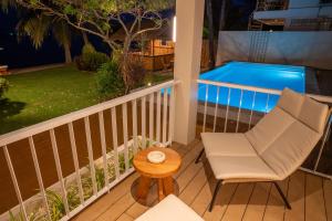 a balcony with a chair and a table and a swimming pool at Baan Bophut Beach Hotel Samui - SHA Extra Plus in Bophut