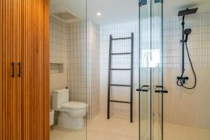 a bathroom with a toilet and a glass shower at Baan Bophut Beach Hotel Samui - SHA Extra Plus in Bophut