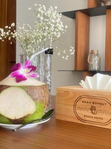 a bowl of fruit on a table with a vase with flowers at Baan Bophut Beach Hotel Samui - SHA Extra Plus in Bophut