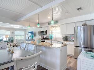 a kitchen with white cabinets and a stainless steel refrigerator at The Austin Pearl in Fort Myers Beach