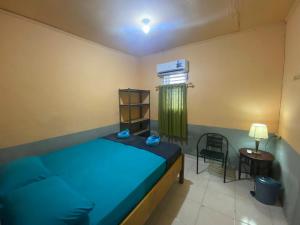a small bedroom with a blue bed and a chair at Harry & Mimin Homestay in Gorontalo +147 photos