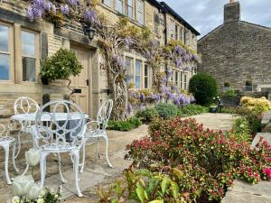eine Terrasse mit weißen Stühlen und Blumen vor einem Gebäude in der Unterkunft Woodlea Cottage in Huddersfield