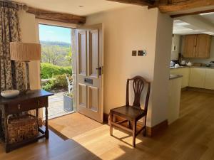 eine Küche mit einem Stuhl, einem Tisch und einer Tür in der Unterkunft Woodlea Cottage in Huddersfield