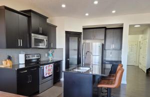 a kitchen with black cabinets and stainless steel appliances at Exquisite Entire 4- Bed rooms vacation home! in Calgary