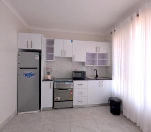 a kitchen with white cabinets and a refrigerator at Cozy Home-Rusororo-near airport in Kigali