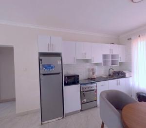 a kitchen with white cabinets and a refrigerator at Cozy Home-Rusororo-near airport in Kigali +7 photos