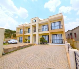 a large yellow building with a parking lot at Cozy Home-Rusororo-near airport in Kigali