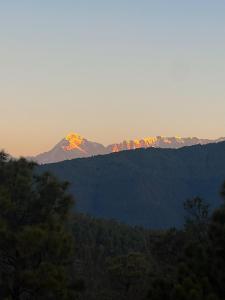 a mountain in the distance with the sun shining on it at The Chitai Life in Almora
