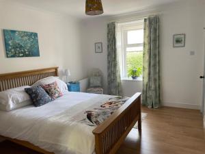 une chambre avec un grand lit et une fenêtre dans l'établissement Glencairn Cottage, à Moffat
