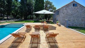 a deck with chairs and an umbrella next to a pool at Villa Fig & Oak in Mlini