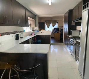 une grande cuisine avec un comptoir et des armoires blancs dans l'établissement Ludinz guest house self catering, au Cap 12 autres photos