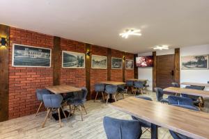 a restaurant with wooden tables and chairs and a brick wall at Willa Radość in Krynica Zdrój