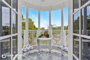 邦加里Bella Abode on Bribie - Loft with Pool的阳台的 ⁇ 染,配有桌椅