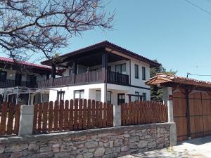 a white house with a fence and a gate at Поповата къща in Krapets
