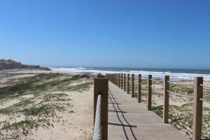 a boardwalk to the beach with the ocean in the background at Casa de Férias Terra e Mar in Póvoa de Varzim