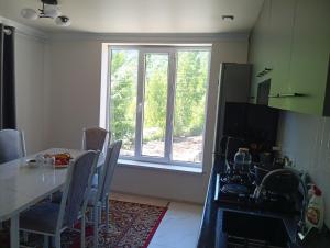 a kitchen with a dining table and a window at Modern Homestay in Arslanbob