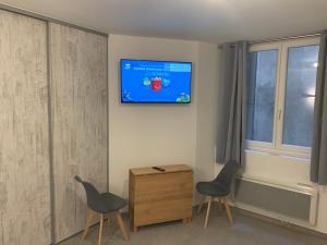 une chambre avec deux chaises et une télévision murale dans l'établissement Grande chambre appartement Clara, à Chambéry