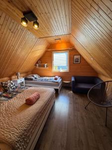 a attic bedroom with two beds and a window at Maharówka - Domki z sauną i balią - Ostrowo - holiday home in Ostrowo