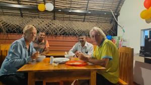 un gruppo di persone seduti intorno a un tavolo di legno di Dark waves villa a Nilaveli