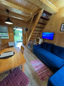 a living room with a blue couch and a table at Maharówka - Domki z sauną i balią - Ostrowo - holiday home in Ostrowo
