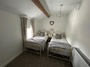 a small room with two beds and a window at The Barn Cottage in Oakworth