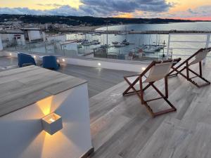 a balcony with chairs and a table and a view of a harbor at North Wind Luxury Home in Vieste