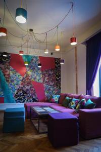 a living room with a purple couch and a colorful wall at Arina Apartments 2 in Braşov