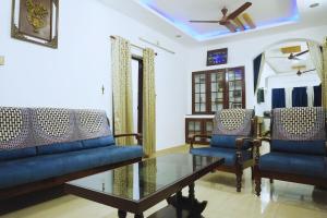 a living room with blue couches and a glass table at 4BHK Independent Garden Villa, heart of the city in Trivandrum