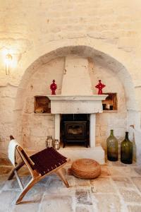 a living room with a stone fireplace and a chair at Trullo Zaira in Alberobello