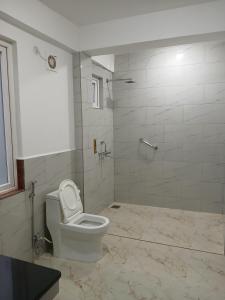 a white bathroom with a toilet and a shower at The Sherpas Rest in Darjeeling