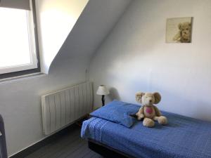 a teddy bear sitting on a bed in a bedroom at Sara's Home 24 in Rouen