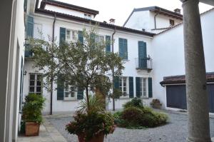 Biały dom z zielonymi okiennicami i drzewem w obiekcie Villa Maghetti - modernized flat in historic palazzo in the center of Luino w mieście Luino