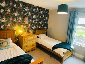 a bedroom with two beds and a floral wall at Willow Cottage Haverigg Millom in Haverigg