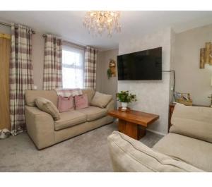 a living room with a couch and a flat screen tv at Willow Cottage Haverigg Millom in Haverigg
