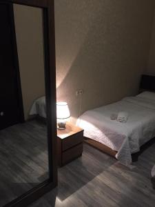 a mirror in a bedroom with a bed and a lamp at Apartament ANASTASIA in Tbilisi City