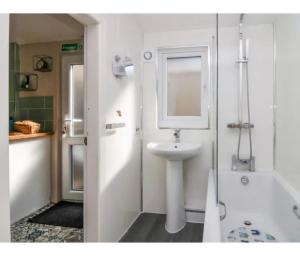 a white bathroom with a sink and a bath tub at Willow Cottage Haverigg Millom in Haverigg +36 photos