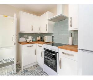 a kitchen with white cabinets and a stove top oven at Willow Cottage Haverigg Millom in Haverigg