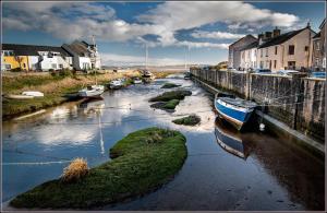 a river with boats in the water and houses at Willow Cottage Haverigg Millom in Haverigg