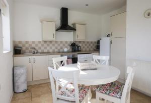 a white kitchen with a white table and chairs at Ballymultimber Cottages - traditional cottages on the Causeway Coast in Limavady