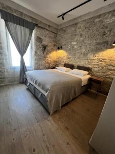 a bedroom with a bed and a stone wall at NisUrla in Urla