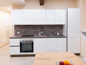 a kitchen with white cabinets and a wooden table at Residenza Dante Luxury Apartment nel Centro Storico in Asolo