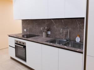 a kitchen with white cabinets and a sink at Residenza Dante Luxury Apartment nel Centro Storico in Asolo