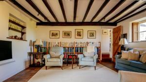 - un salon avec deux chaises et une étagère avec des livres dans l'établissement Stunning 4-Bed Thatched Cottage in Oxfordshire!, à Ledwell