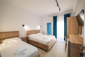 a bedroom with two beds and a flat screen tv at Hotel Perla Ksamil in Ksamil +174 photos