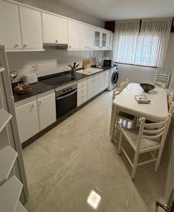 a kitchen with white cabinets and a table and a table and chairs at Apartamento Barbanza Arousa in Boiro