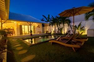 a house with a pool and two chairs and an umbrella at Simple & Magical Villas PRAYA in Seminyak