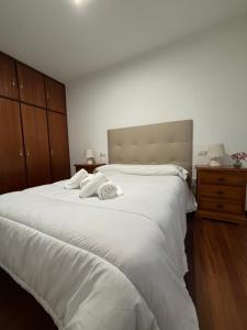 a bedroom with a large white bed with towels on it at Apartamento Barbanza Arousa in Boiro